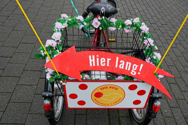 Fahrradanhänger geschmückt mit Schild und Blumen