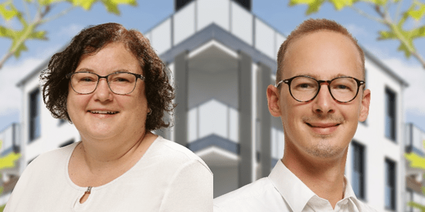 Frau mit Brille und mittellangen, lockigen Haaren in weißer Blus und junger Mann mit Brille und weißem Hemd vor einem modernen Gebäude.