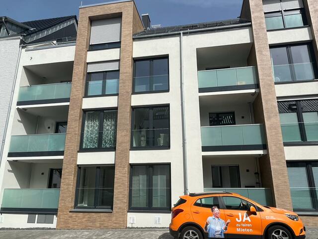 Viergeschossiges Wohnhaus mit oranges Auto davor