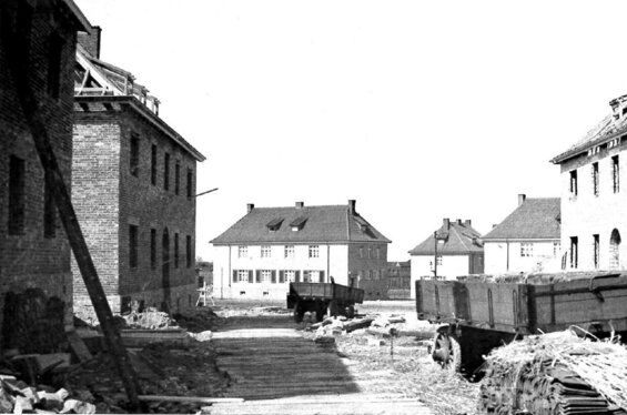 Eine Schwarz-Weiß-Fotografie zeigt eine Straßenszene aus der Sighardstraße in Paderborn mit Backsteingebäuden, einem Holzwagen und einem Haufen Schutt vor einem klaren Himmel.