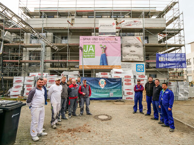 Handwerker verschiedener Gewerke stehen vor einer Baustelle