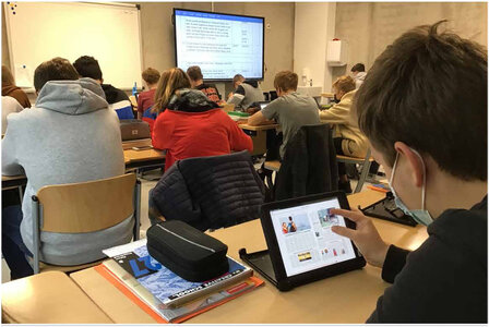 Schuler in einem Klassenraum lesen via Tabletts in der Tageszeitung Neue Westfälische
