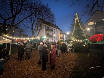 Weihnachtlich geschmückter Platz auf dem viele Menschen stehen.