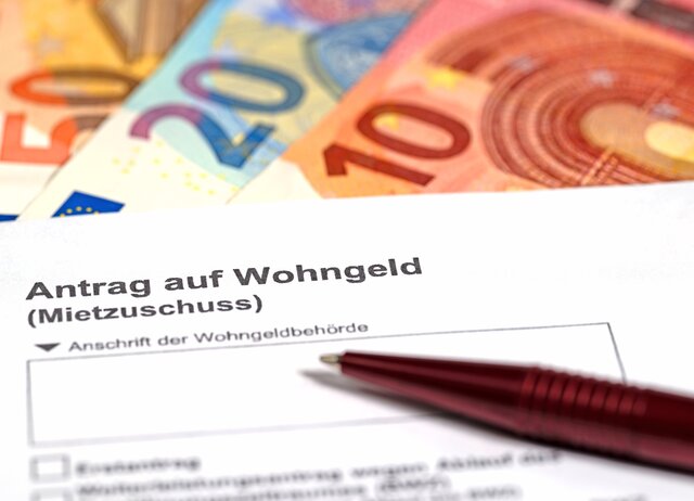 Euroscheine liegen unter einem Antragsformular auf Wohngeld darüber ein Kugelschreiber